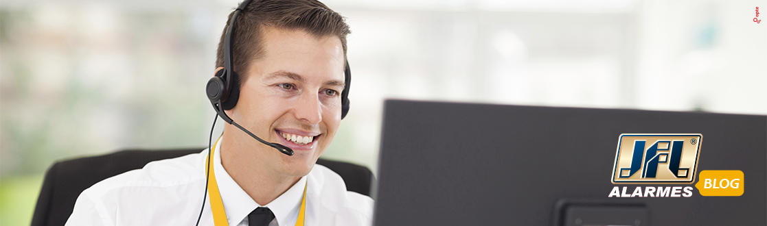 Homem com headphone sorrindo na frente da tela de um computador prestando atendimento ao cliente